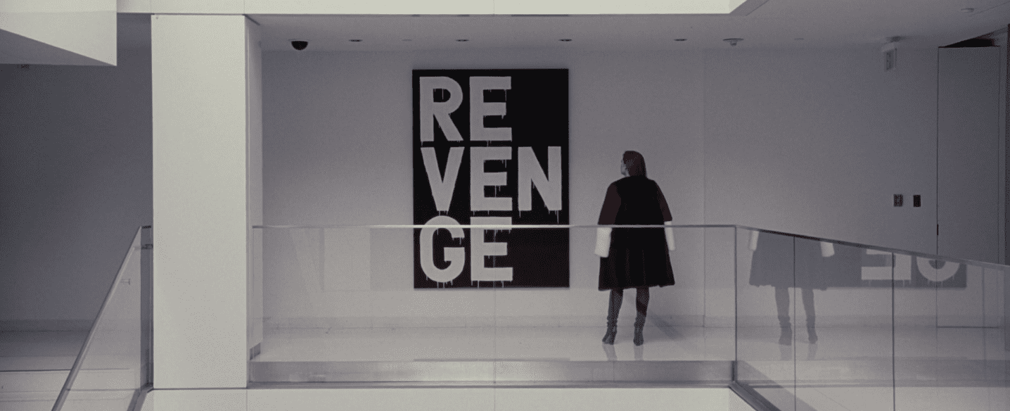 Amy Adams en face d'un tableau sur lequel est écrit REVENGE