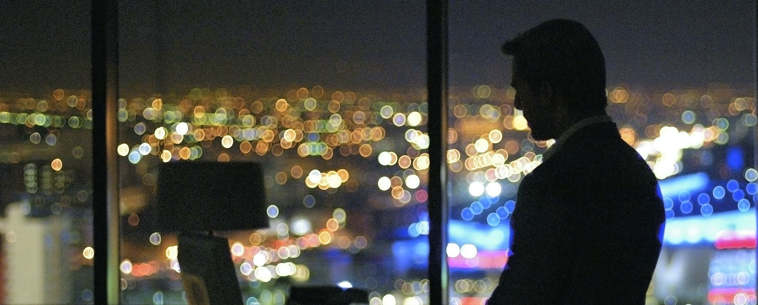 Tom Cruise devant la fenêtre d'un building de nuit avec vue sur Los Angeles